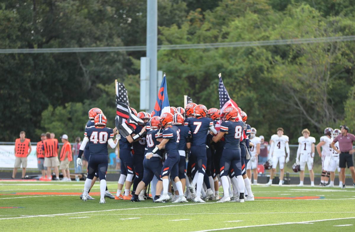 Varsity football players huddle around each other before the game. 