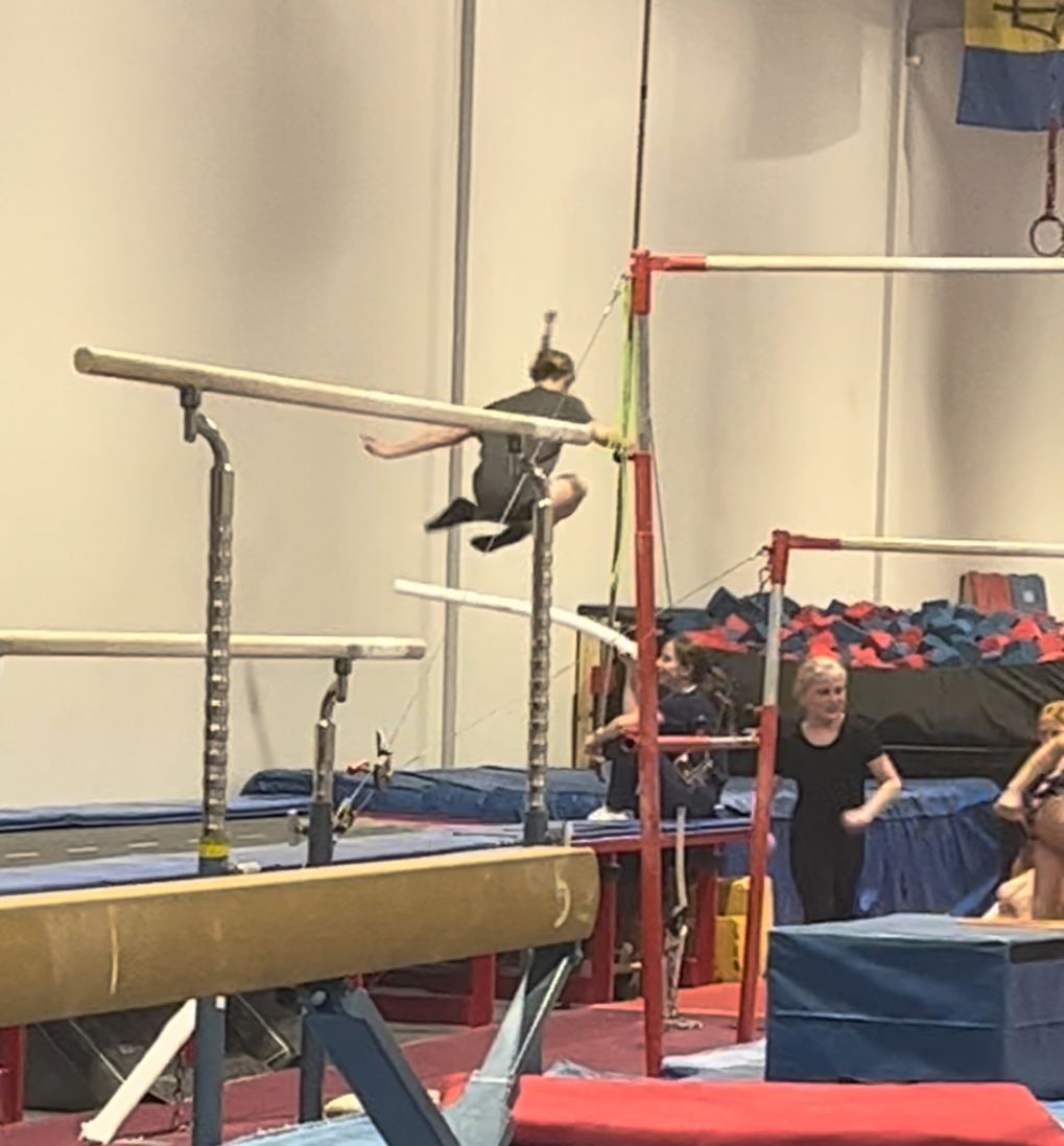 A person jumping over a pool noodle at gymnastics. 