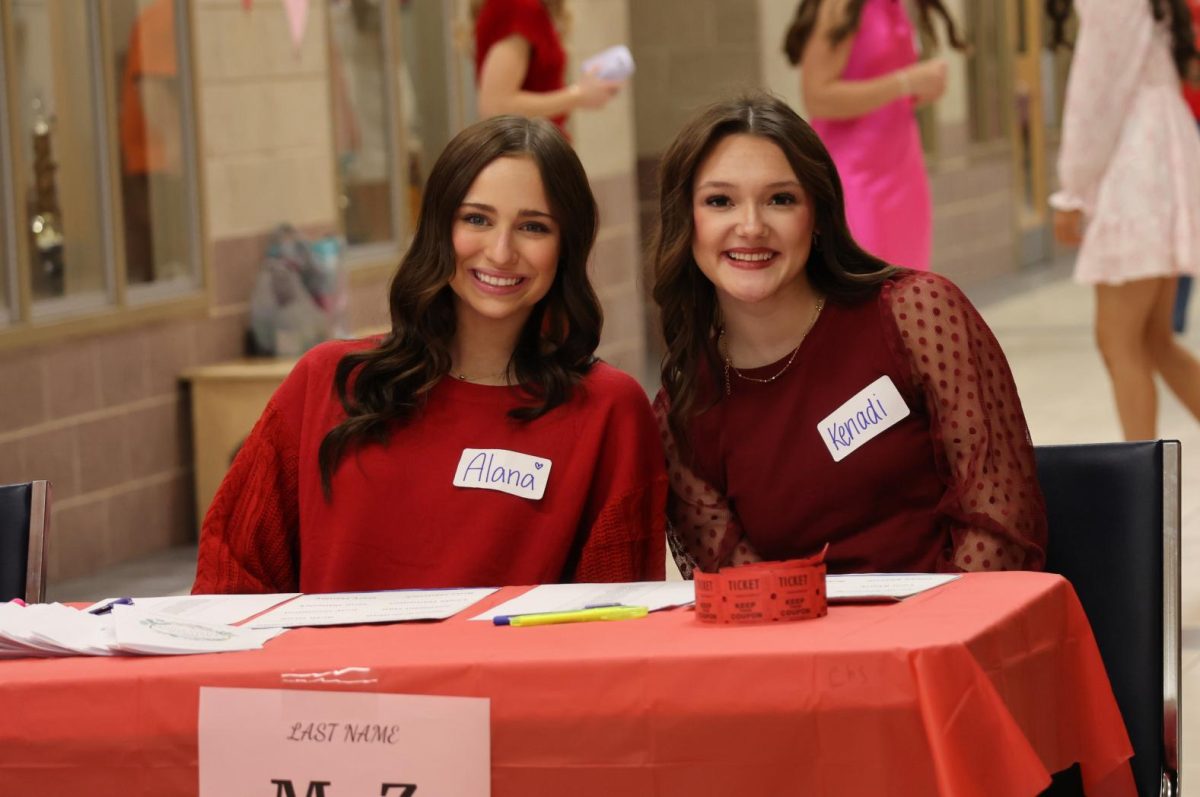 Juniors Alana Rausenberger and Kenadi Compton pose for a photo while working the sign-in table at the 2025 Valentine's Day Luncheon. 