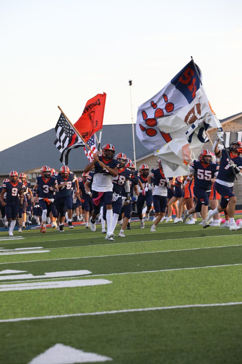 The football team is doing run-out at the beginning of the game. This was against Marion at Carterville on August 29.