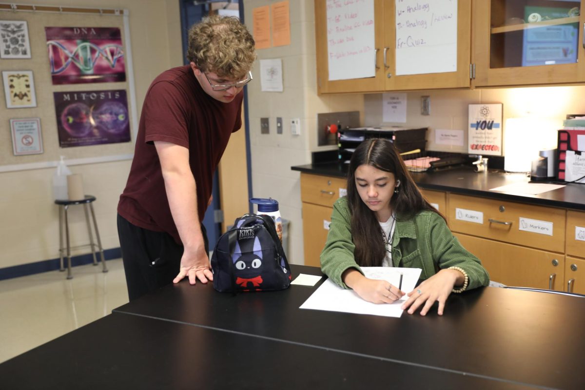 Sophomore and Eco-Club founder Keller Beyers discusses the club with sophomore Lorenzo Mariag, who works on a poster to promote the paper recycling initiative. 