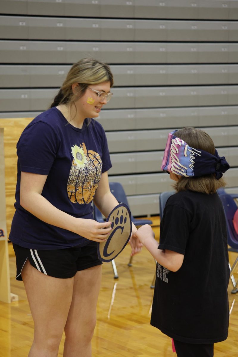 Sophomore, HS Publications member, Lucy Gossett blindfolding a student from Tri-C Elementary so they could play the game.