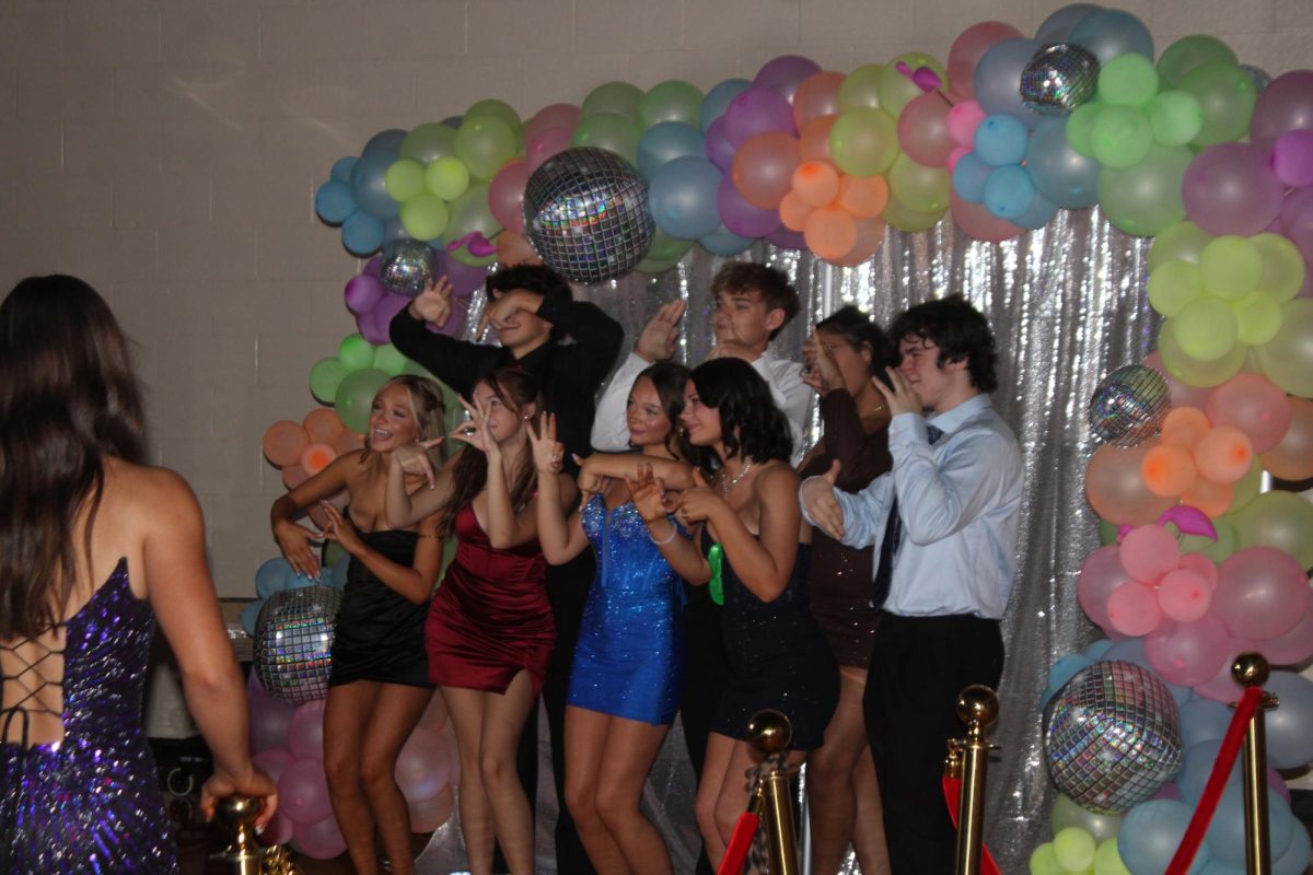 A group of students pose in front of a backdrop during homecoming.