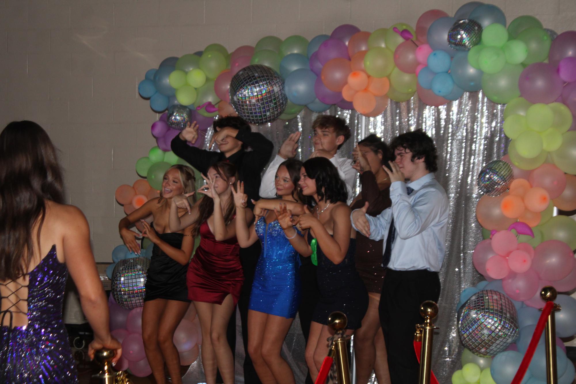 A group of students pose in front of a backdrop during homecoming.